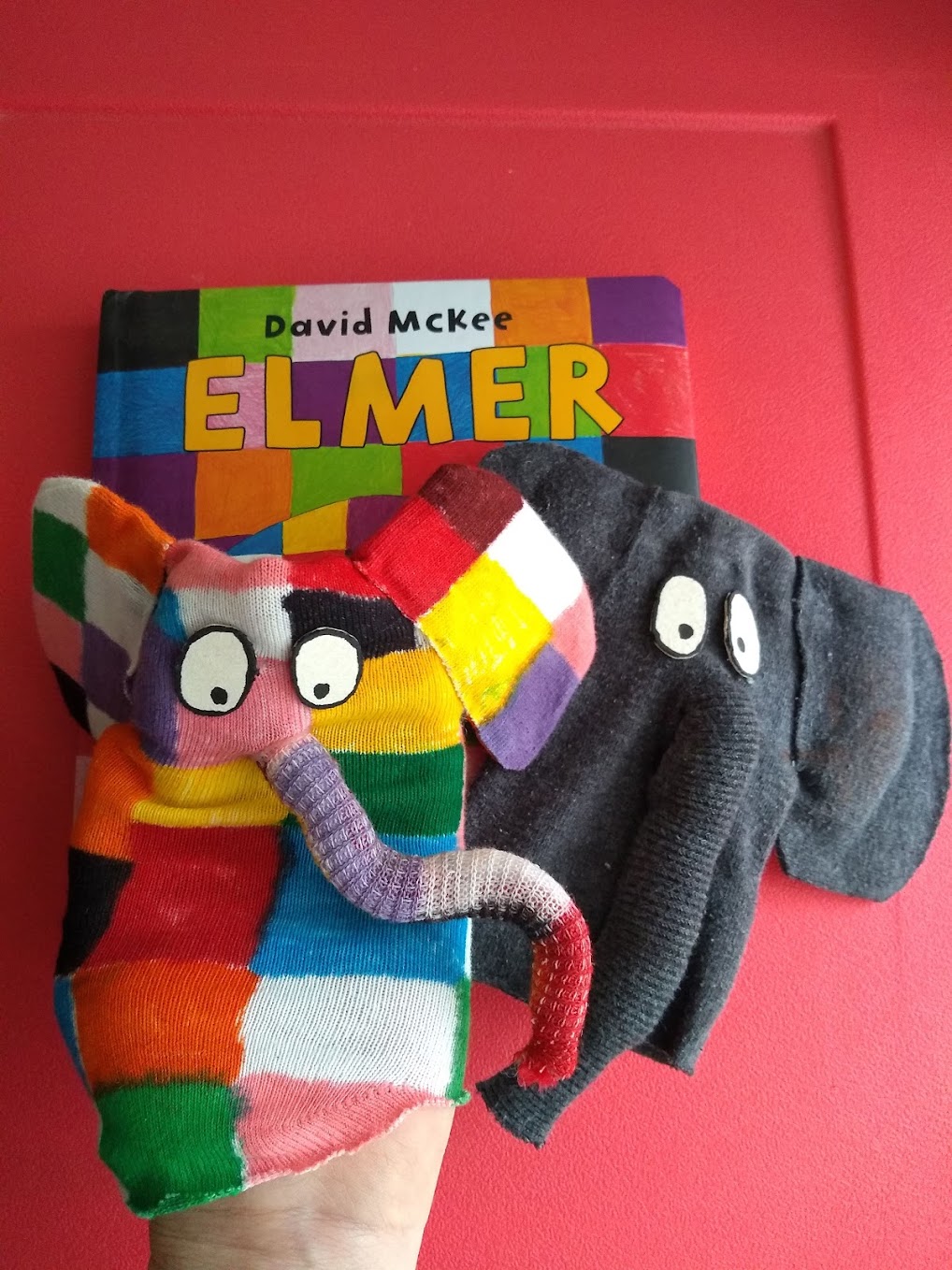 Pupazzo dell'elefante Elmer fatto a mano accanto al libro Elmer di David McKee