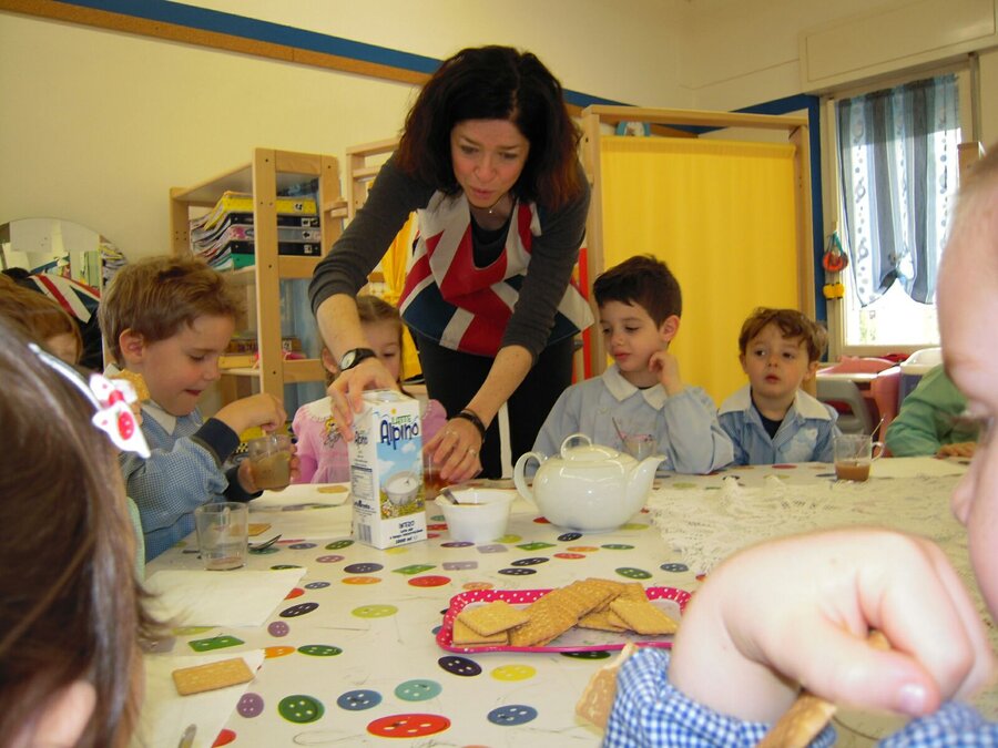 Bambini a tavola con tè, latte e biscotti durante l'attività Tea Time