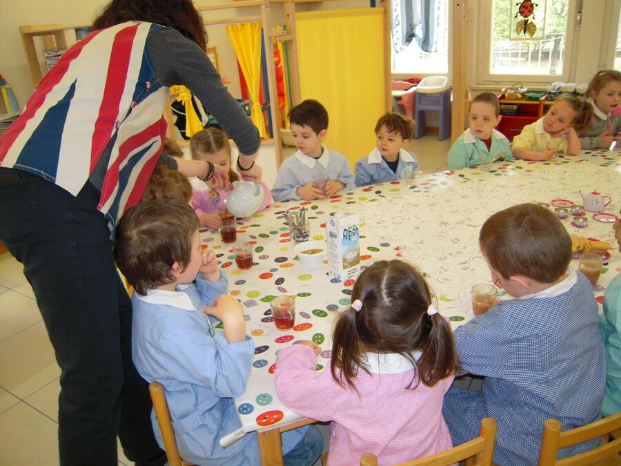 Luisa versa il tè ai bambini seduti attorno al tavolo decorato per il Tea Time